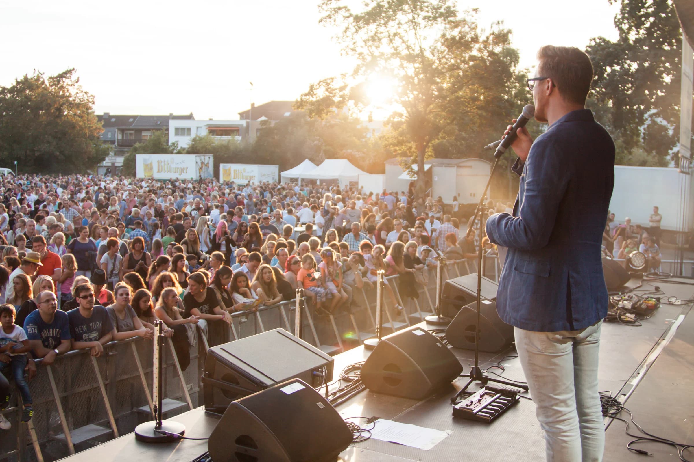 Blick von der Bühne auf ein großes Open-Air-Publikum im Abendlicht