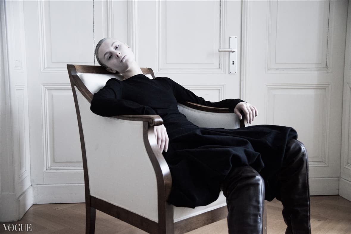 Model in a black look seated in a historic armchair